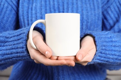 Photo of Woman holding blank white ceramic mug, closeup. Mockup for design