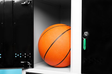 Photo of Open locker with basketball ball on light blue background, closeup