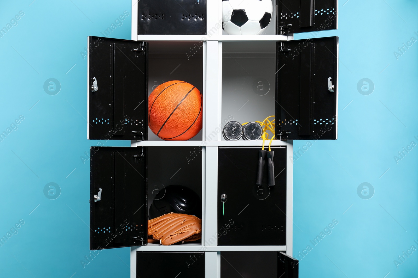 Photo of Open lockers with sport equipment on light blue background