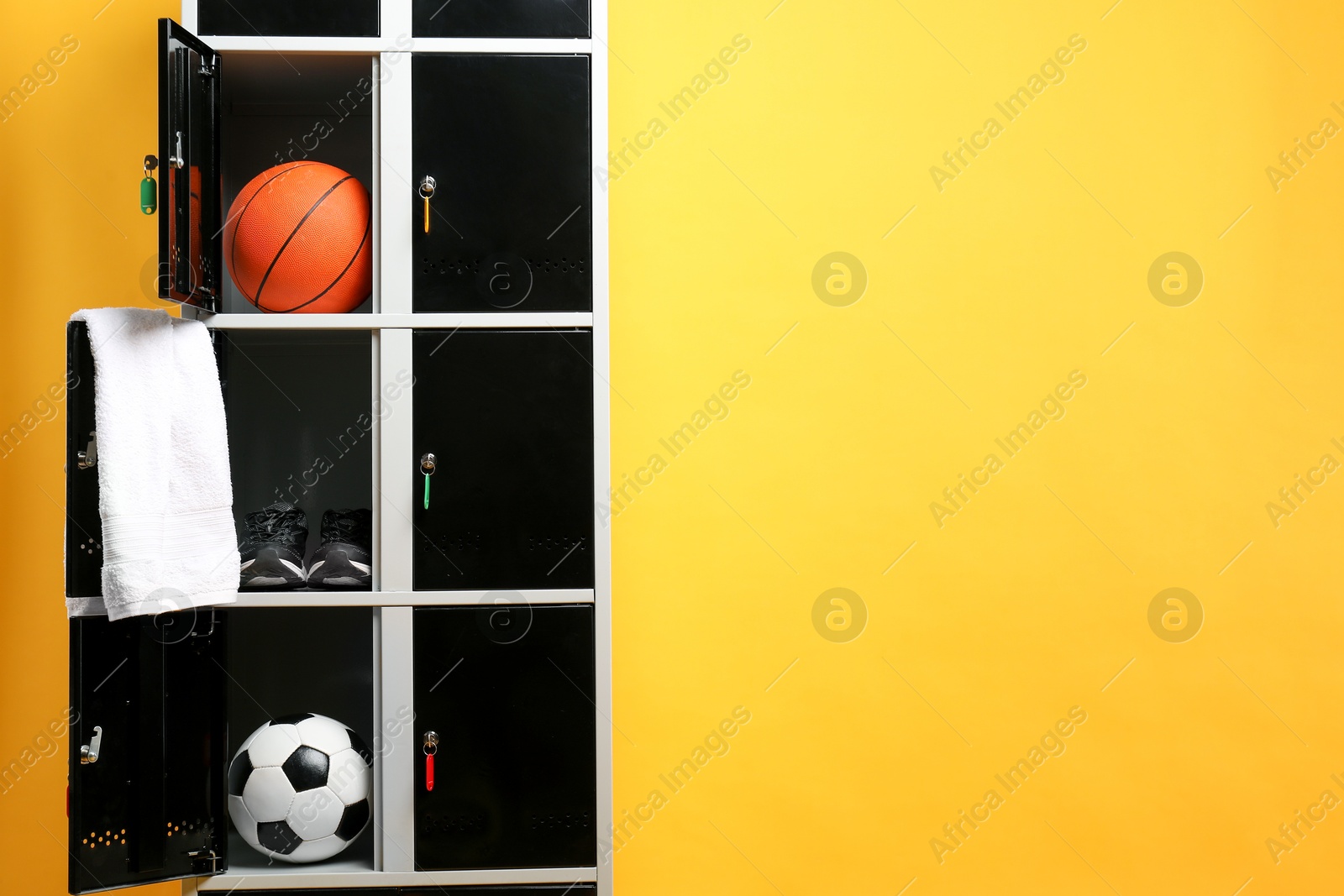 Photo of Open lockers with sport equipment on orange background, space for text