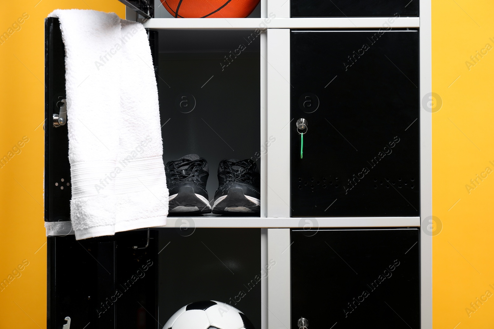 Photo of Open lockers with sport equipment on orange background