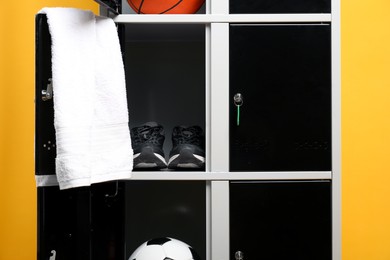 Open lockers with sport equipment on orange background