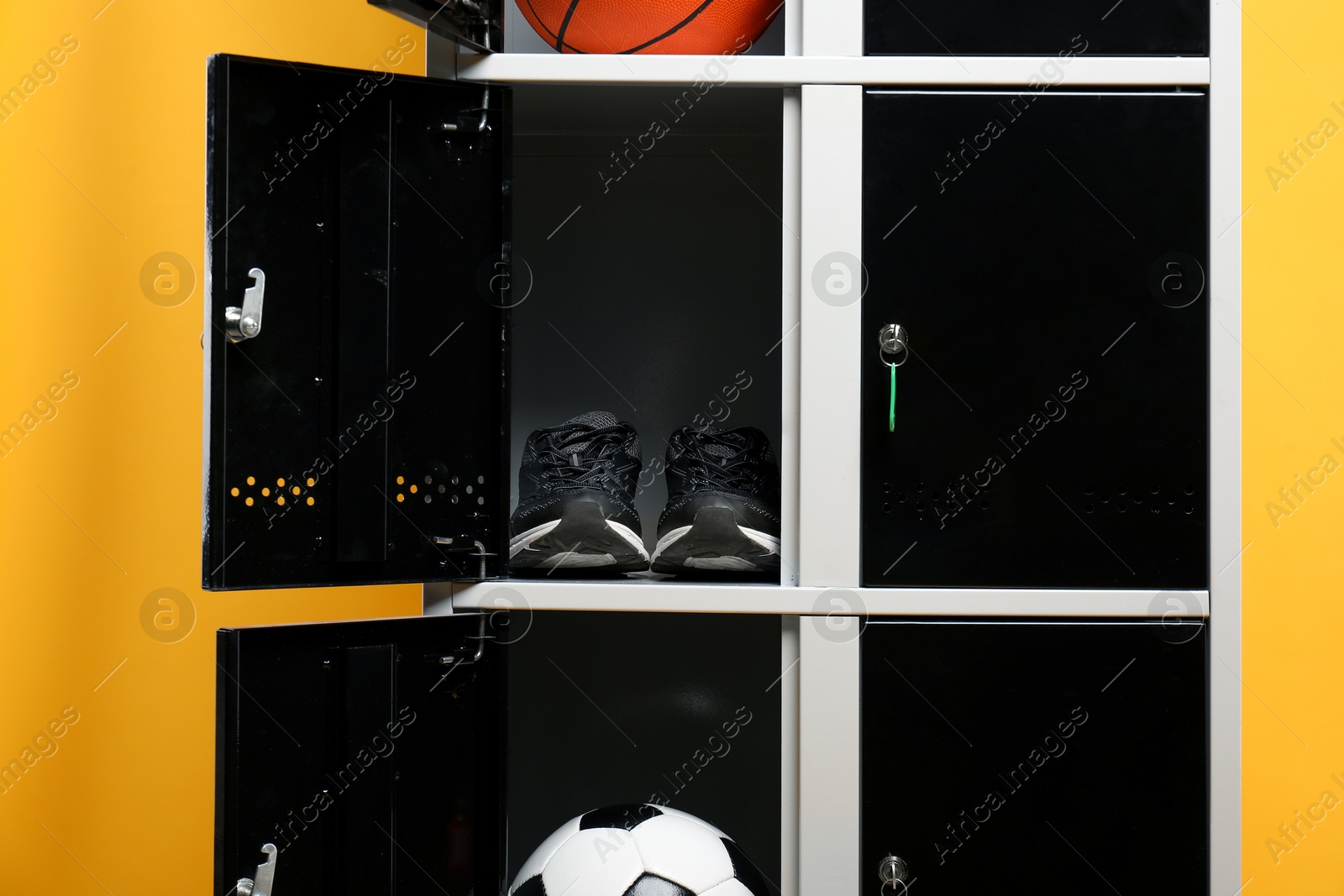 Photo of Open lockers with sport equipment on orange background