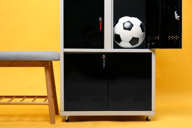 Open locker with soccer ball and bench on orange background