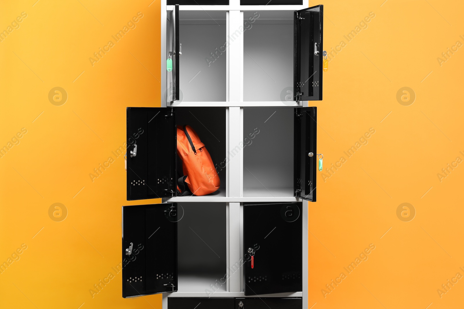 Photo of Open locker with backpack on orange background