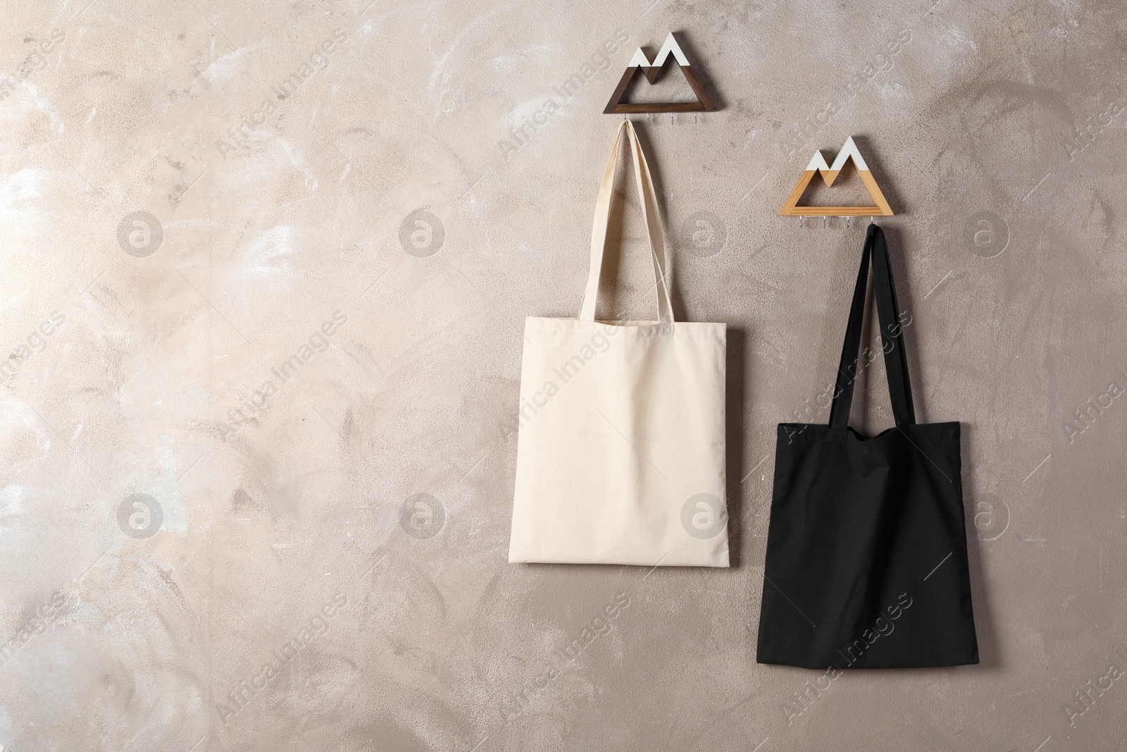 Photo of Eco bags hanging on grey wall,. Mockup for design