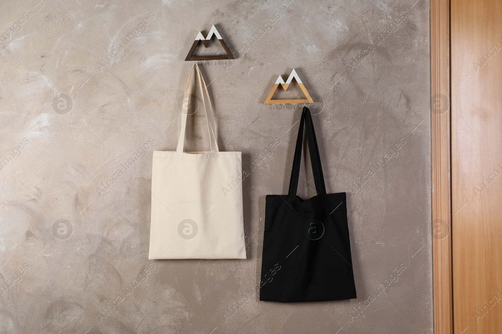 Photo of Eco bags hanging on grey wall. Mockup for design