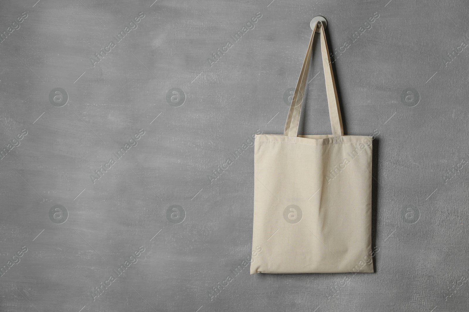 Photo of One eco bag hanging on grey wall. Mockup for design