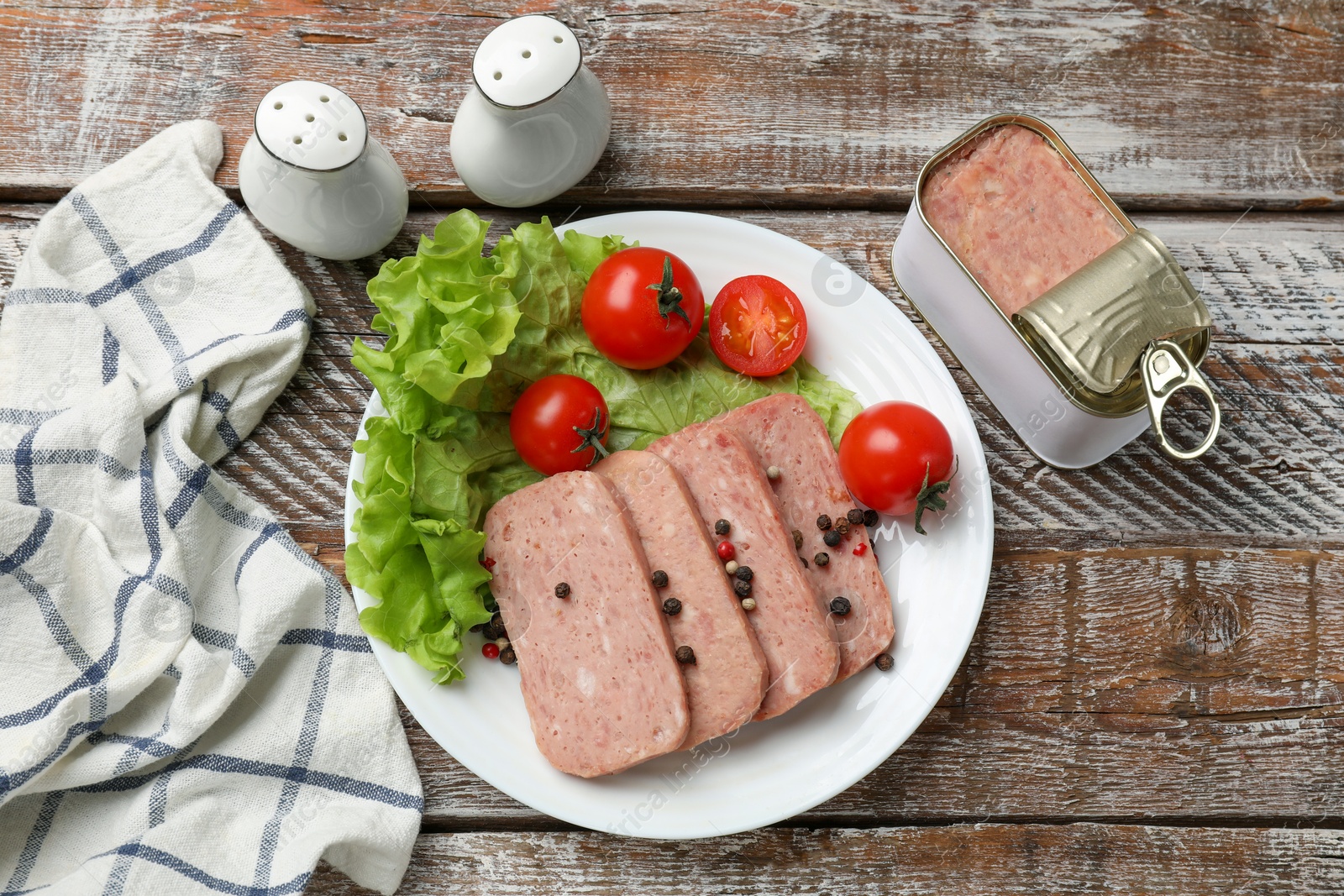 Photo of Tasty canned meat, tomatoes, lettuce and spices on wooden table, top view