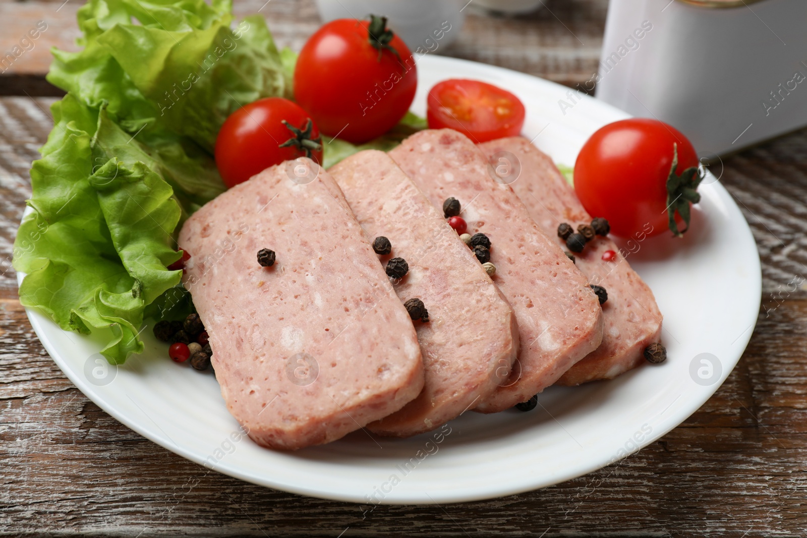 Photo of Tasty canned meat, tomatoes, lettuce and spices on wooden table, closeup