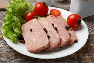 Tasty canned meat, tomatoes, lettuce and spices on wooden table, closeup