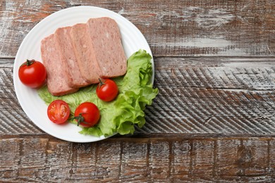 Photo of Tasty canned meat, tomatoes and lettuce on wooden table, top view. Space for text