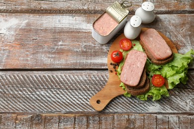 Photo of Tasty canned meat, bread, tomatoes, spices and lettuce on wooden table, top view. Space for text