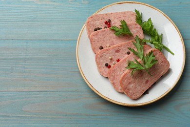 Photo of Tasty canned meat, parsley and peppercorns on light blue wooden table, top view. Space for text