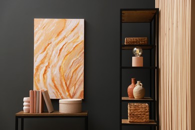 Photo of Console table with decor and shelving unit near grey wall in room. Interior design