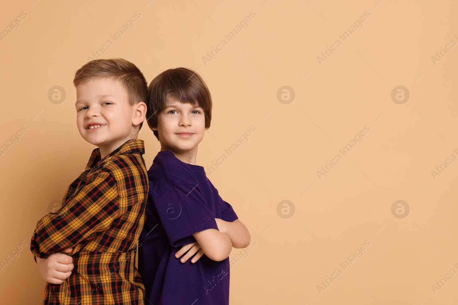 Photo of Portrait of cute brothers on beige background. Space for text