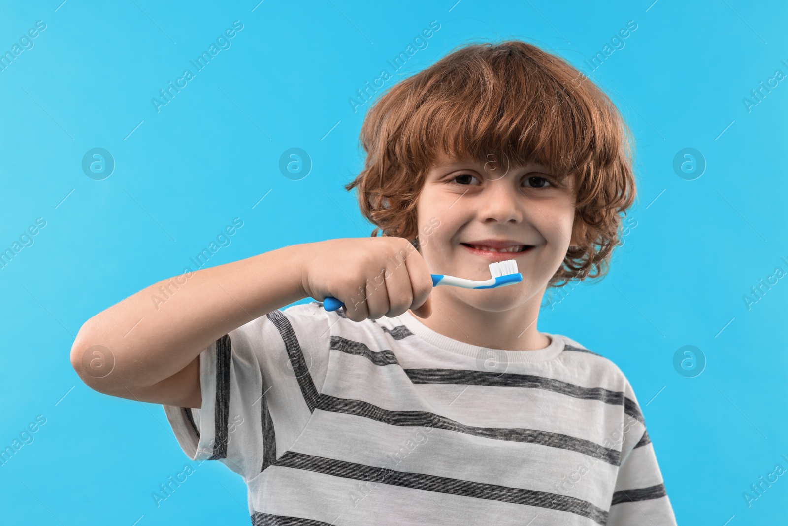 Photo of Cute boy with toothbrush on light blue background