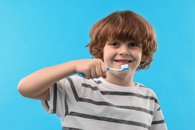 Photo of Cute boy with toothbrush on light blue background