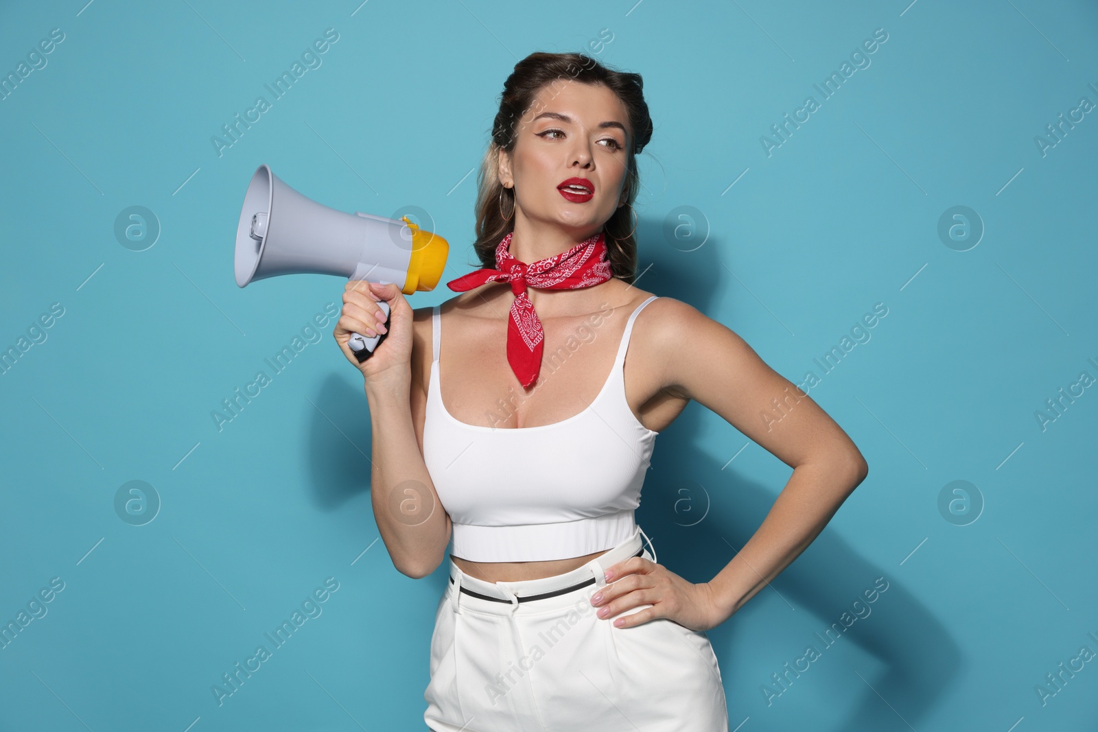 Photo of Attractive pin-up woman with megaphone on light blue background