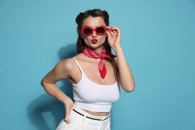 Photo of Attractive pin-up woman in sunglasses on light blue background