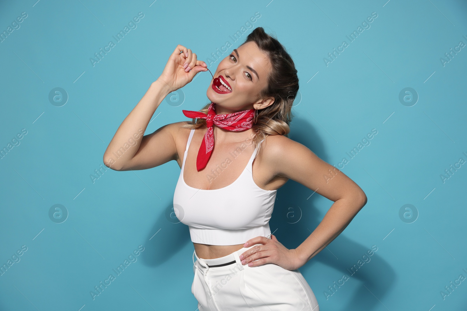 Photo of Attractive pin-up woman with cherry on light blue background