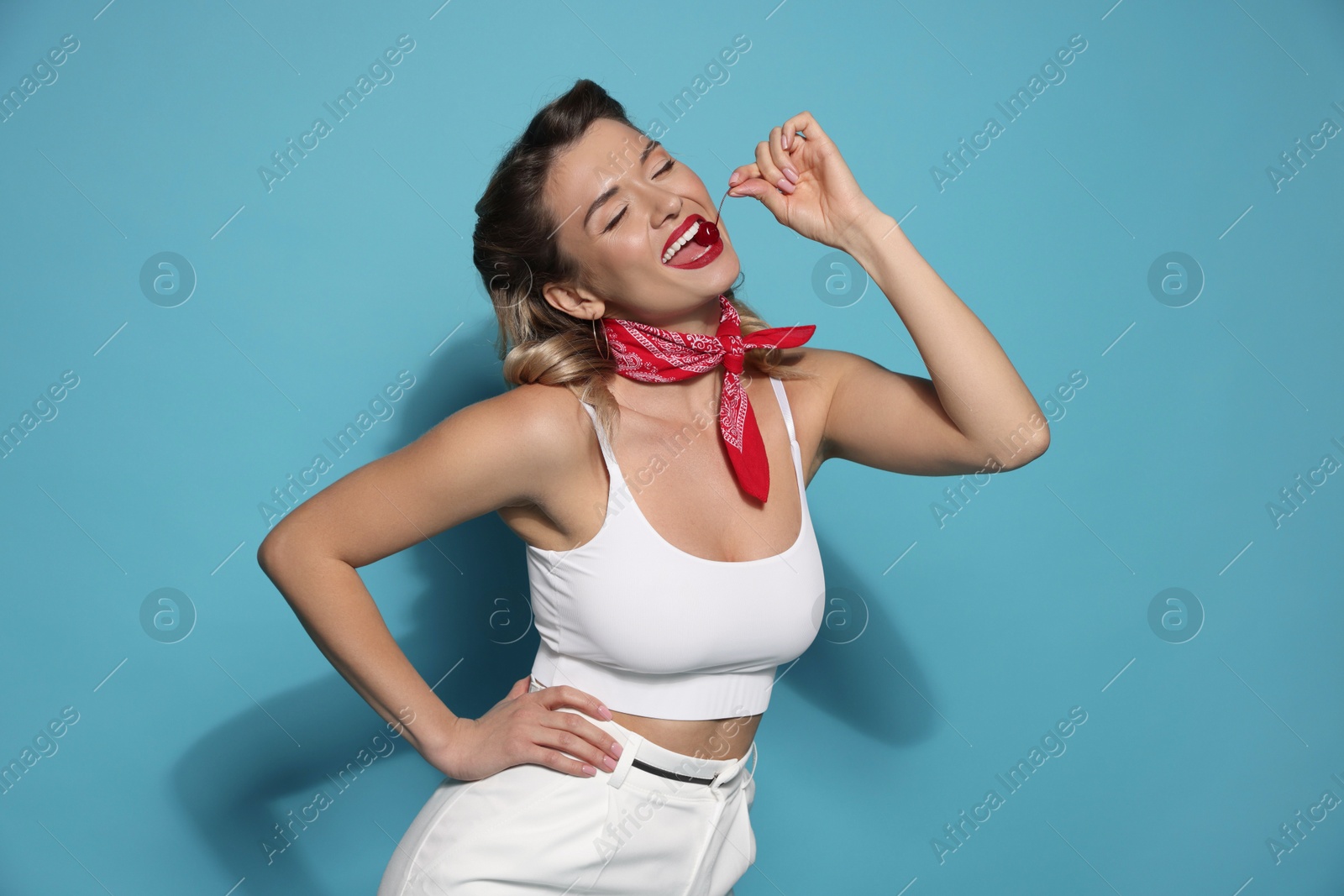 Photo of Attractive pin-up woman with cherry on light blue background