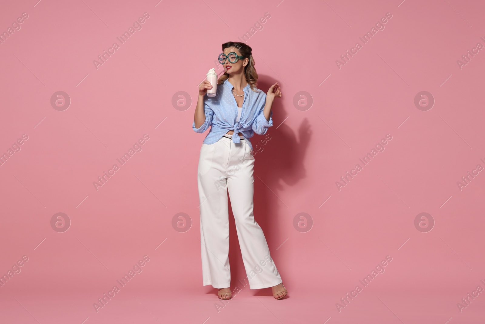 Photo of Attractive pin-up woman with milk shake on pink background