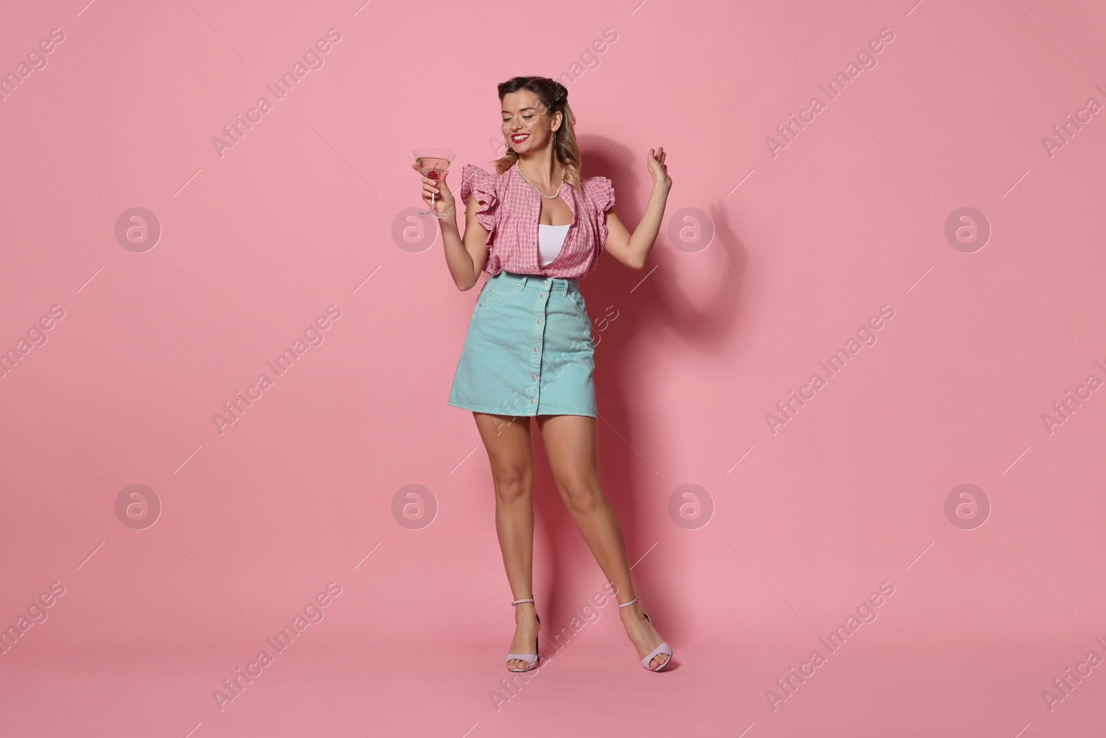 Photo of Happy pin-up woman with cocktail on pink background