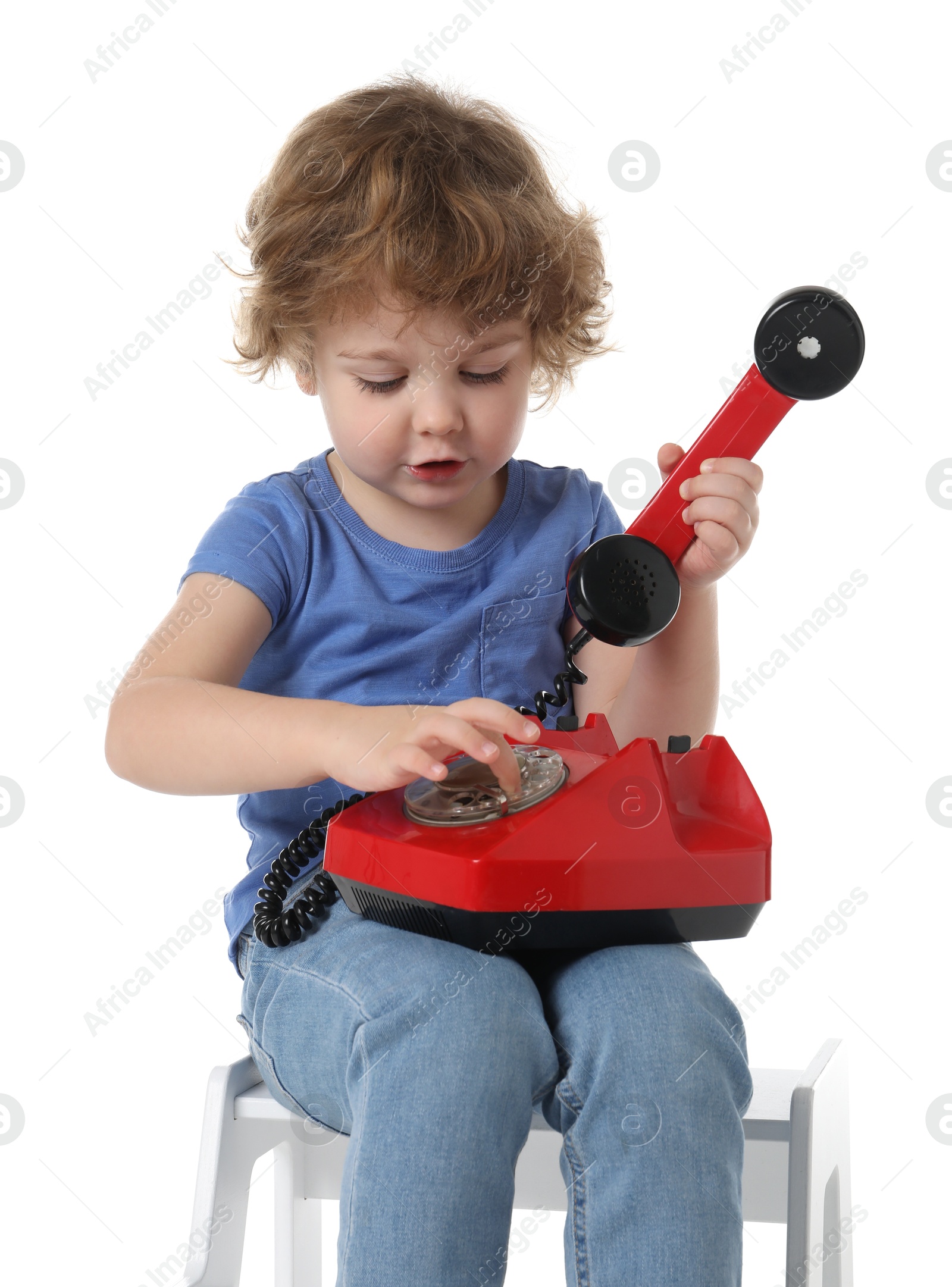 Photo of Cute little boy with telephone on step stool against white background