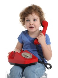 Photo of Cute little boy with telephone on stool against white background