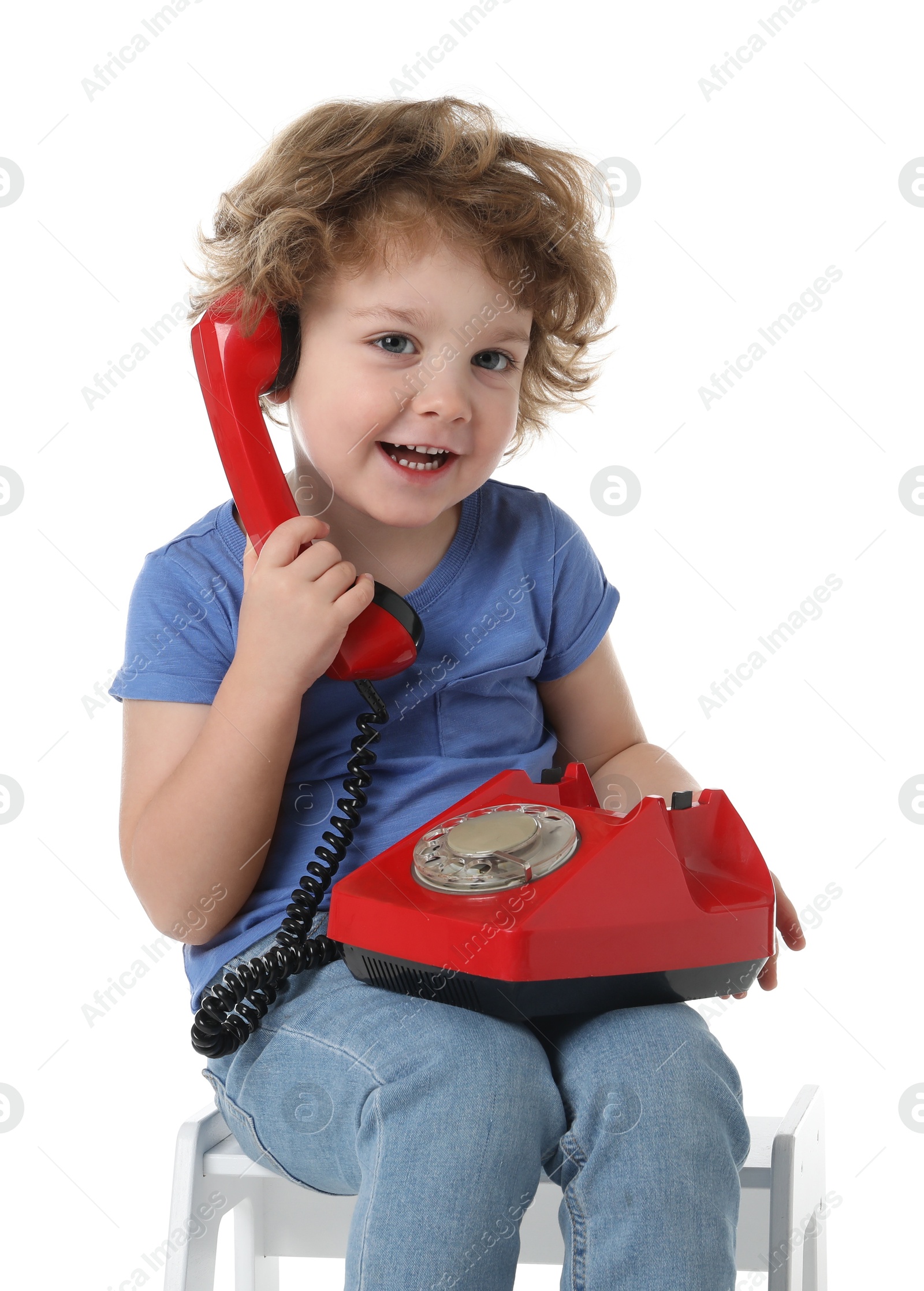 Photo of Cute little boy with telephone on step stool against white background