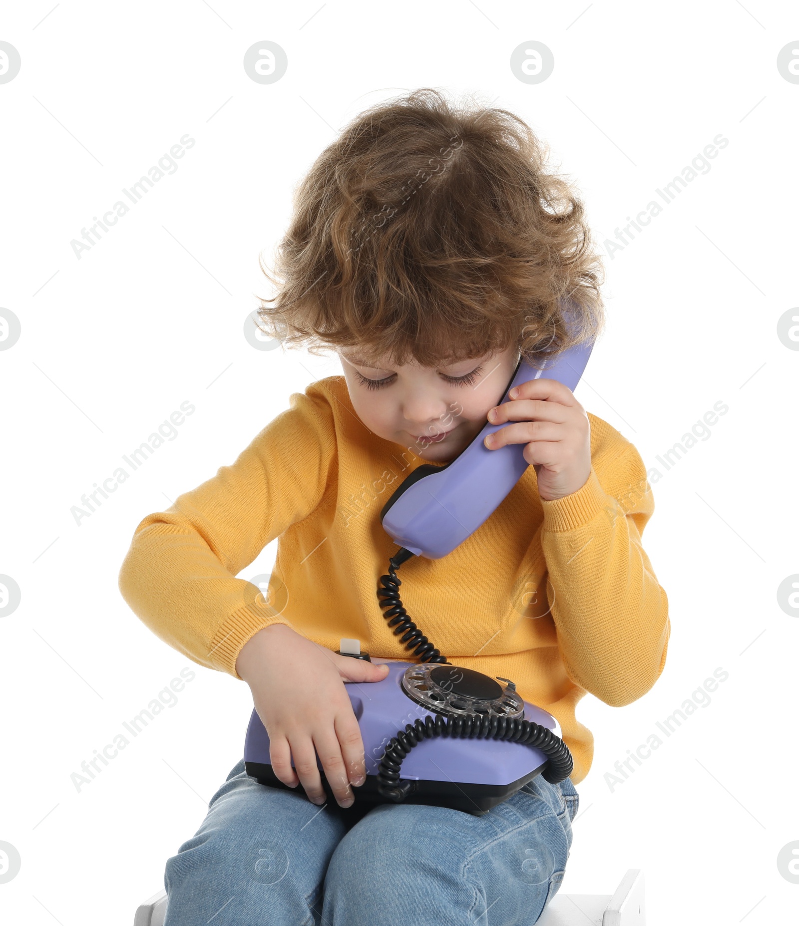 Photo of Cute little boy with telephone on stool against white background