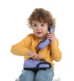 Photo of Cute little boy with telephone on stool against white background