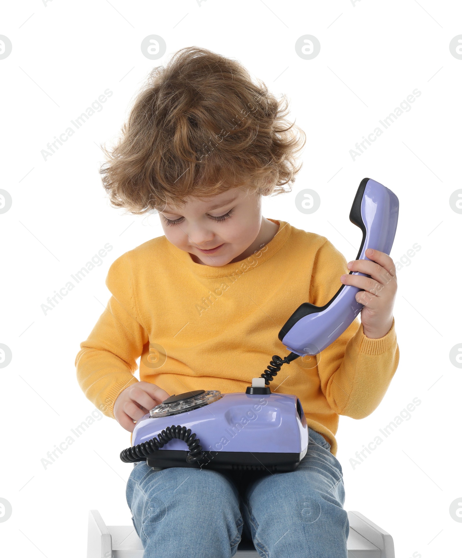 Photo of Cute little boy with telephone on stool against white background