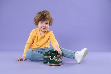 Photo of Cute little boy with old telephone on violet background