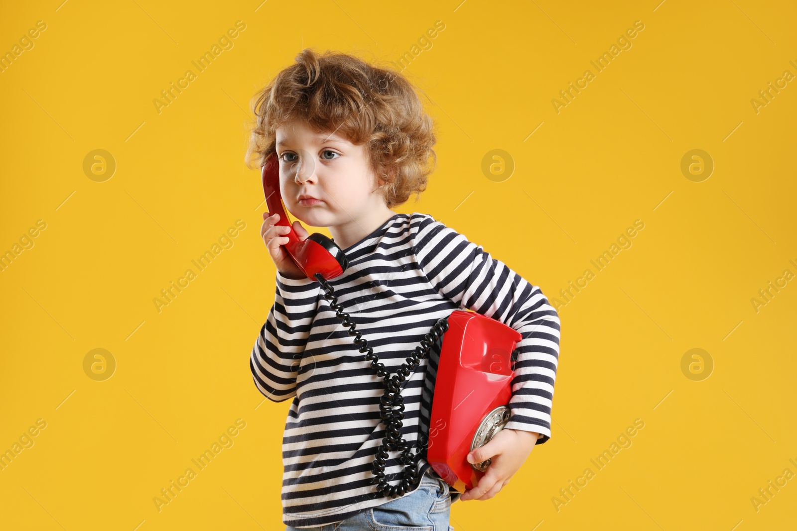 Photo of Cute little boy with telephone on orange background