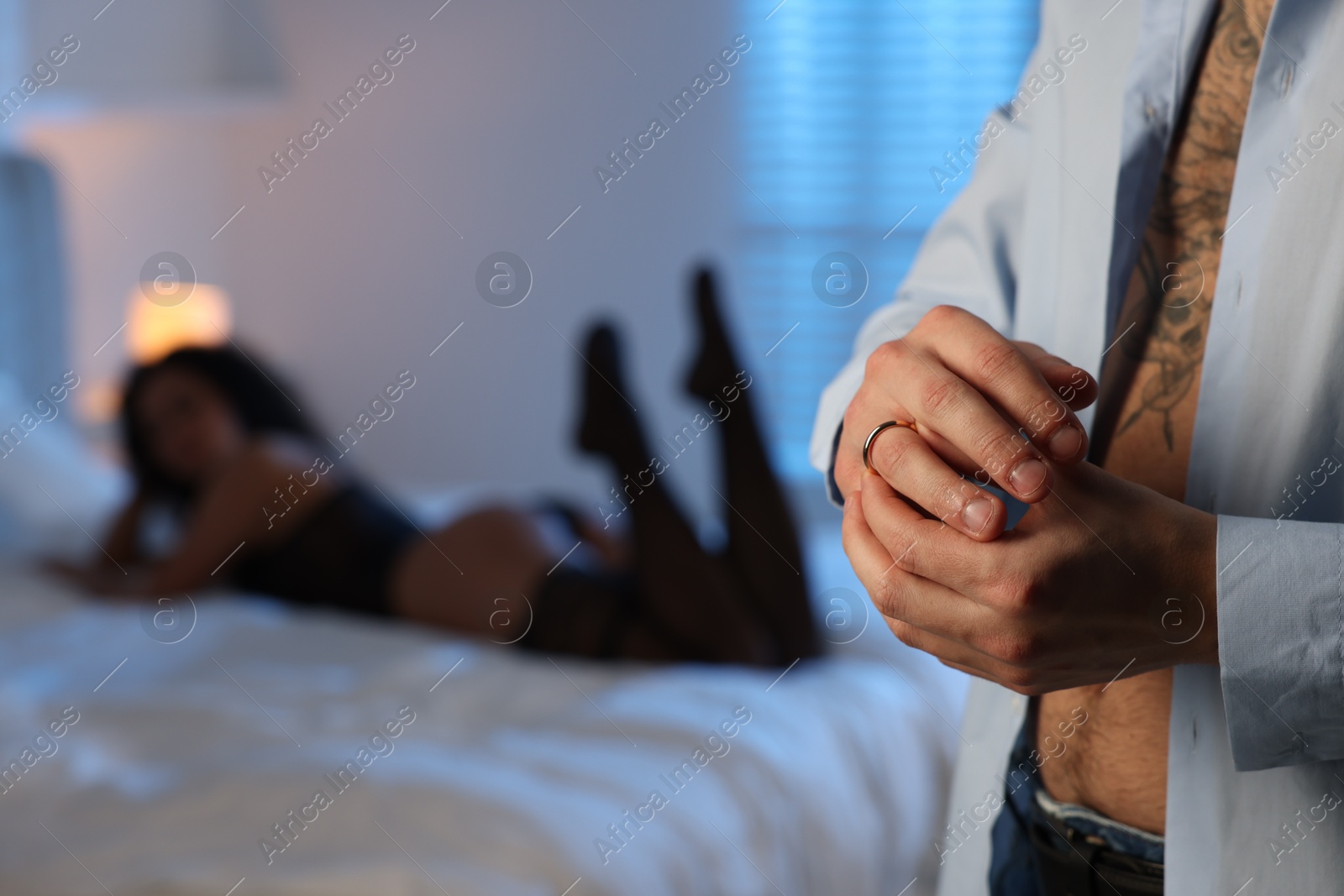 Photo of Betrayal. Unfaithful man taking off engagement ring before enjoying time together with mistress at home, closeup