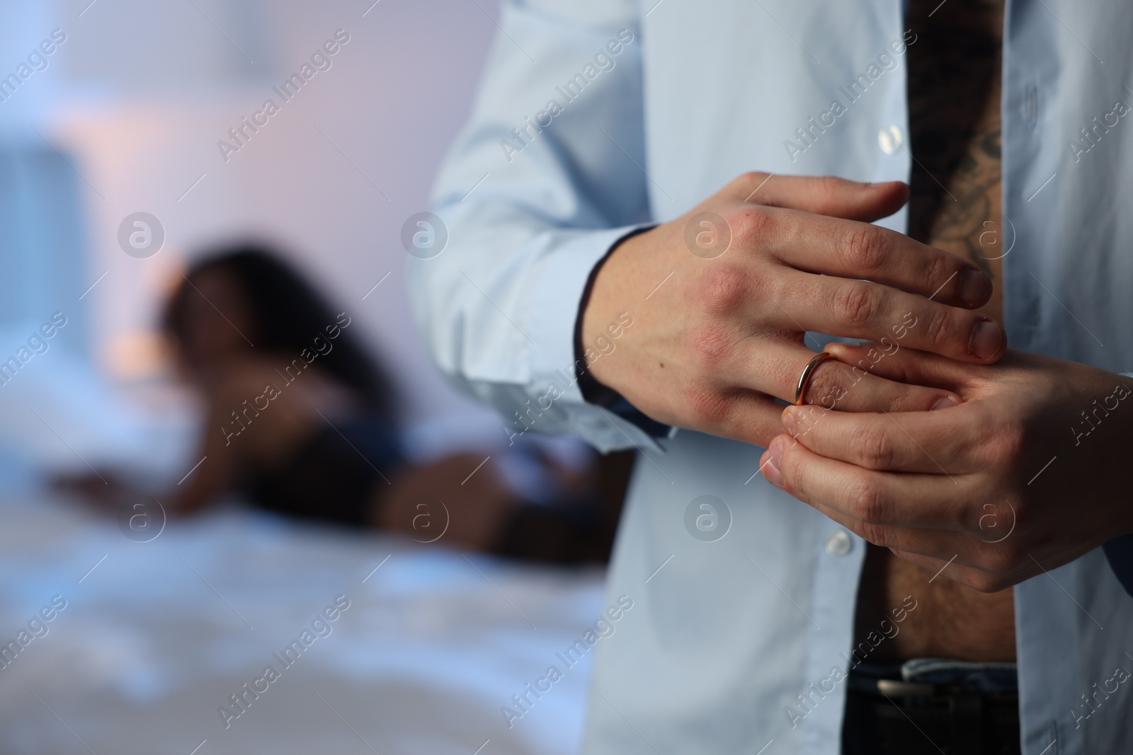 Photo of Betrayal. Unfaithful man taking off engagement ring before enjoying time together with mistress at home, closeup