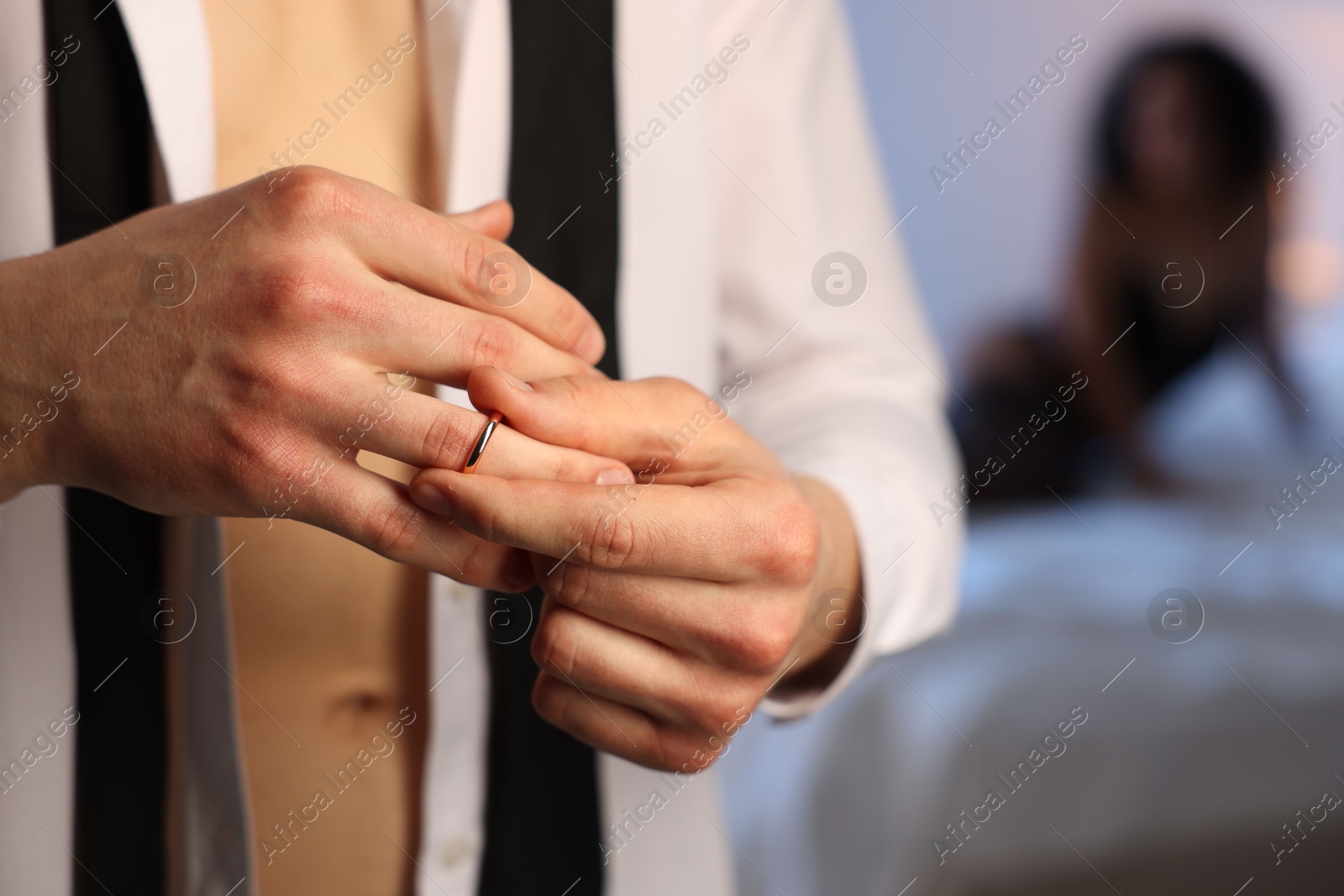 Photo of Betrayal. Unfaithful man taking off engagement ring before enjoying time together with mistress at home, closeup