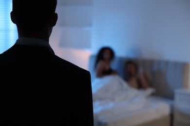 Photo of Betrayal. Husband catching his wife with her lover in bed, back view. Space for text