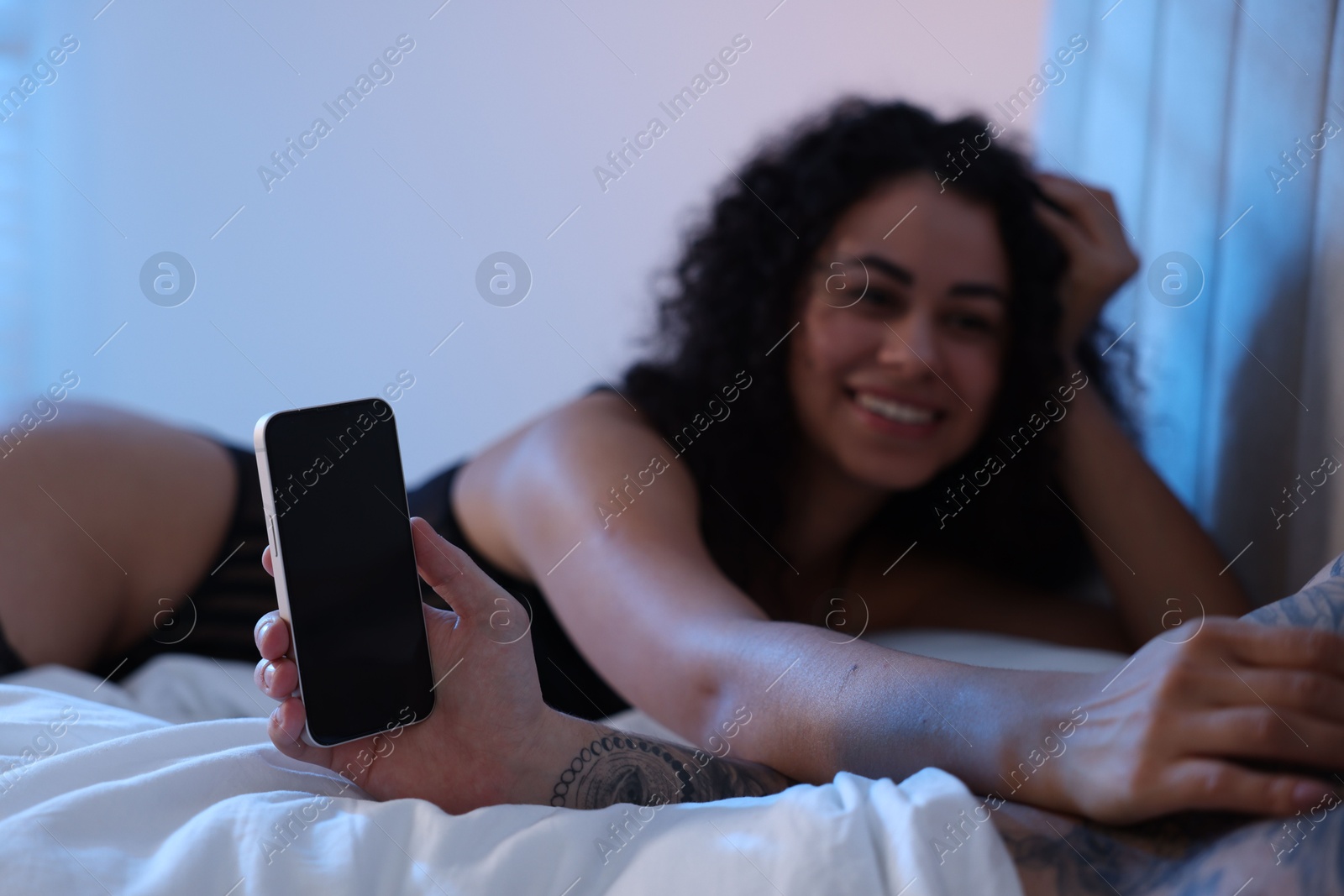 Photo of Betrayal. Man with smartphone and his mistress on bed, closeup