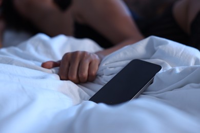 Photo of Betrayal. Woman having sex with her lover on bed, focus on smartphone