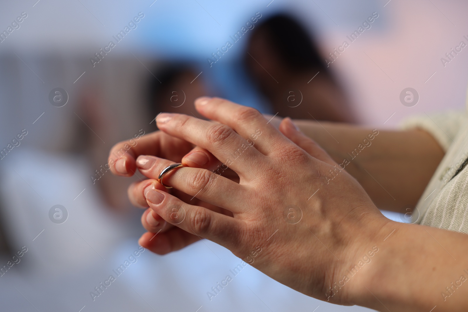 Photo of Betrayal. Wife taking off engagement ring after catching her husband with mistress in bed, selective focus