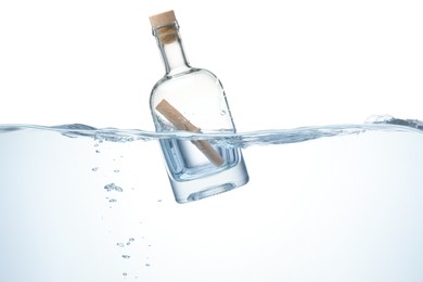 Photo of Corked glass bottle with rolled letter in water on white background