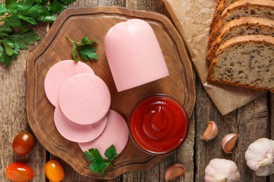 Photo of Tasty boiled sausage, ketchup, tomatoes, spices and bread on wooden table, top view