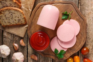 Photo of Tasty boiled sausage, ketchup, tomatoes, spices and bread on wooden table, top view