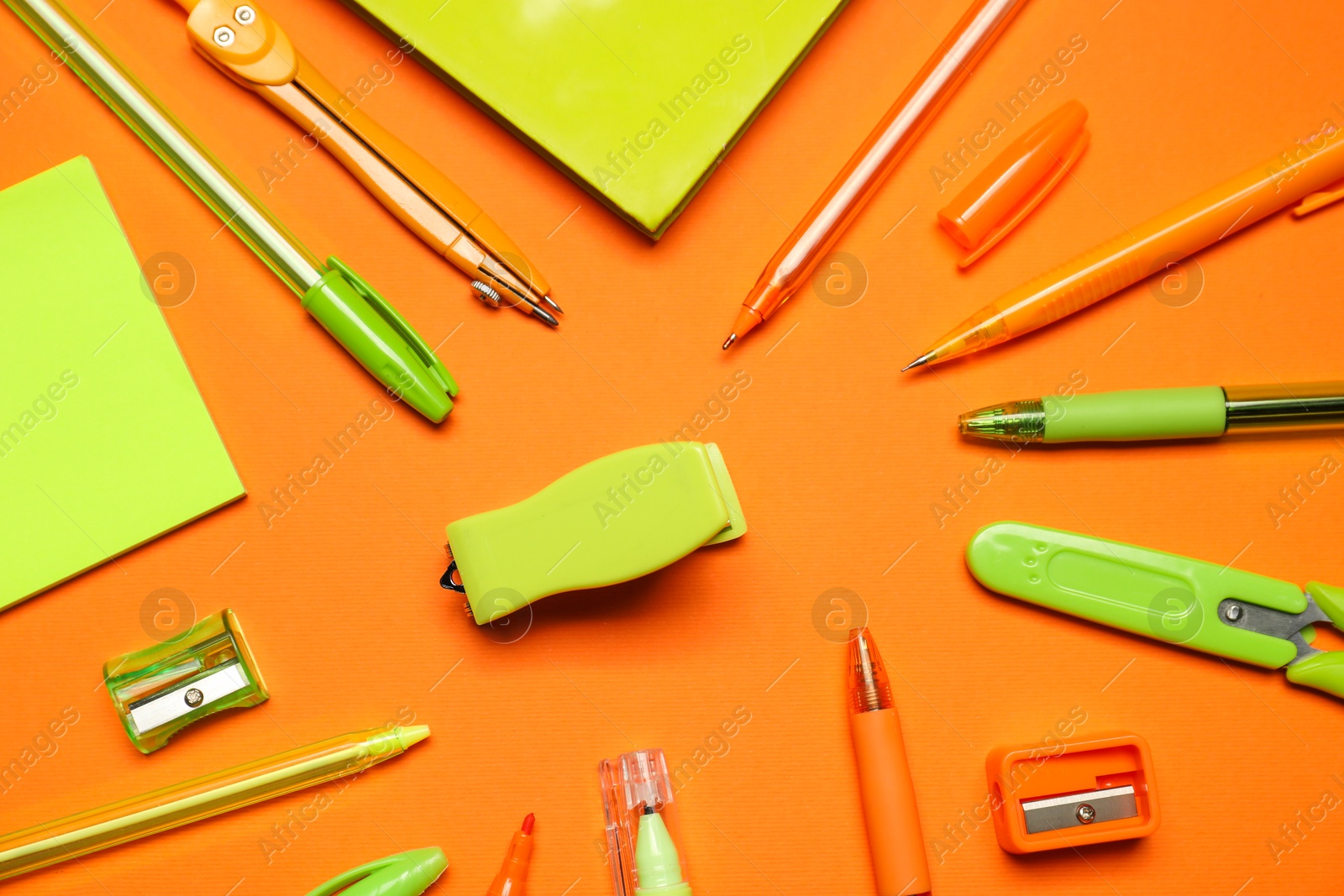 Different stationery on orange background, flat lay Photo of Different stationery on orange background, flat lay