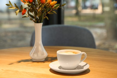 Photo of Cup of delicious coffee on wooden table in cafe