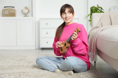 Photo of Happy woman playing ukulele on floor at home