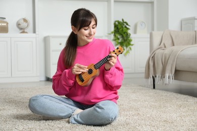 Photo of Happy woman playing ukulele on floor at home